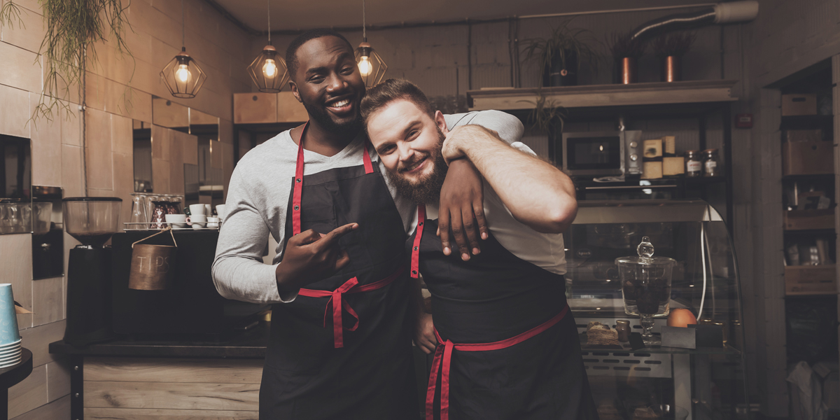 two happy male baristas in a cafe setting